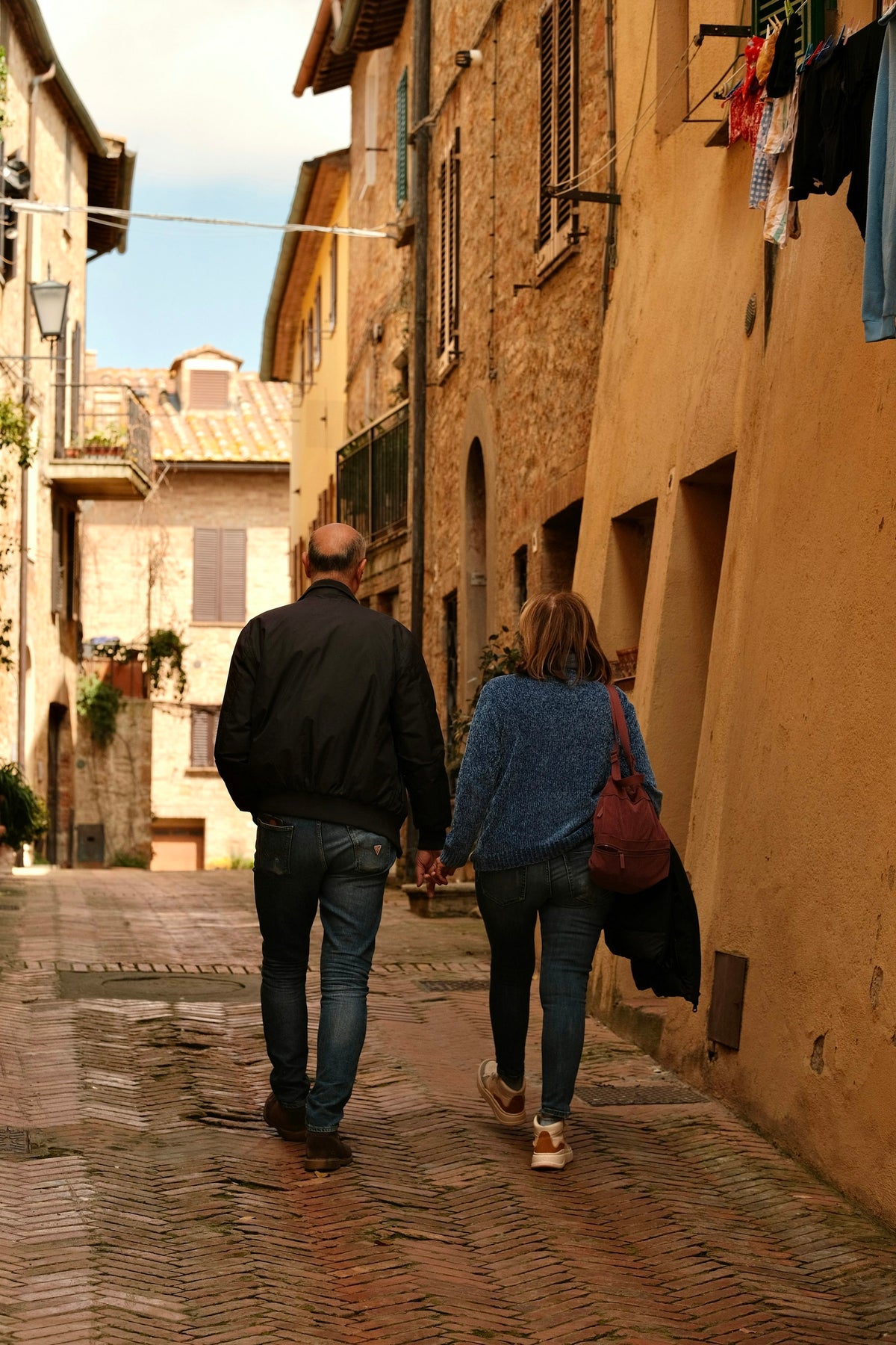Pareja paseando de la mano por una calle empedrada de Toscana